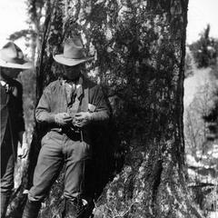 Beneath tree at the abandoned Irwin claim, Apache National Forest, Arizona, 1910, face shaded by hat