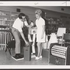 A pharmacist demonstrates the use of an oxygen tank to a saleswoman