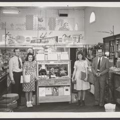 Sales staff stand next to a drugstore monogramming display