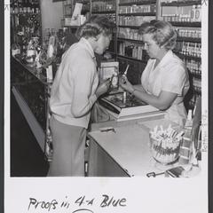 A clerk helps a woman make selection at drugstore cosmetics counter