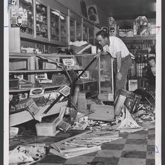 Man bends over to view debris of damaged drugstore
