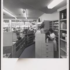 A pharmacy staff member works behind the prescription counter