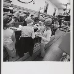 Women sit at a drugstore lunch counter looking at products