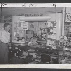 A man stands near a drugstore display of men's goods