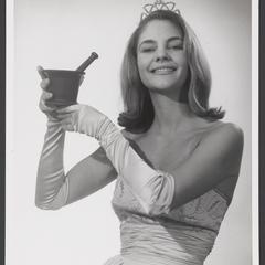 Tiara-wearing woman holds a mortar and pestle