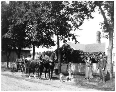 Kate and Ellen Nelson in front of their house with dog and horse-drawn carriage