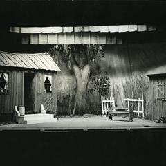 Stage set for an outdoor scene, a run-down one-room house, stable, and yard