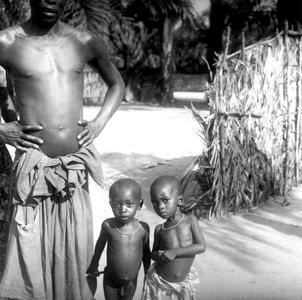 Two Young Kuba-Bieng Children Posing with Their Father Outside Their Compound