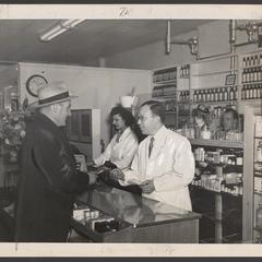 Pharmacy staff assist a customer at the prescription counter