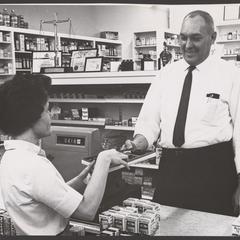 A pharmacist offers a box of chocolates for sampling