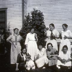 Women and children pose outside a home