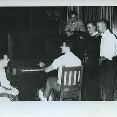 Sigma Tau Gamma members playing and listening to the piano