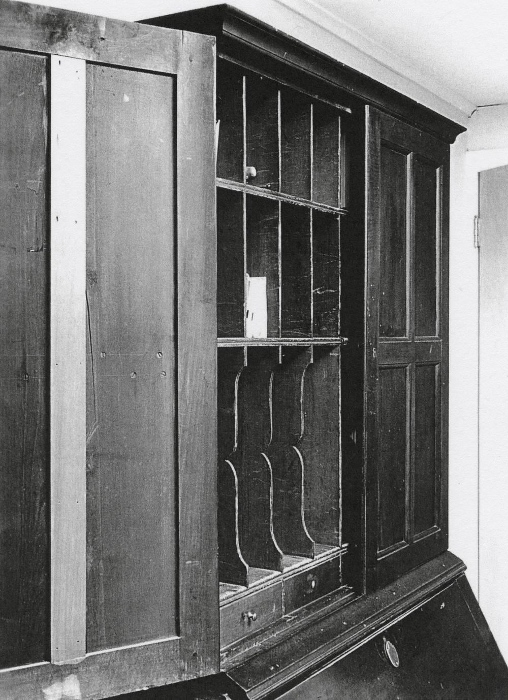 Black and white photograph of a desk and bookcase.
