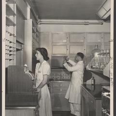 Pharmacy staff work behind the prescription counter