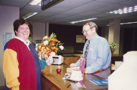 Library Director Tom Fitz helping a smiling patron