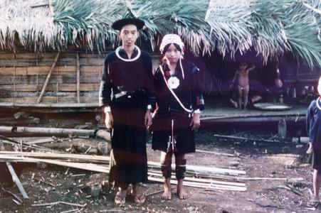 Akha husband and wife stand in front of their house in the village of Phate in Houa Khong Province