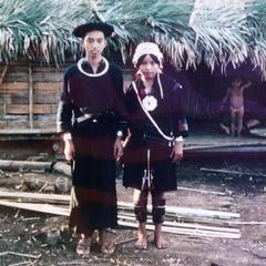 Akha husband and wife stand in front of their house in the village of Phate in Houa Khong Province