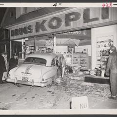 Onlookers stand near a car that drove into a drugstore