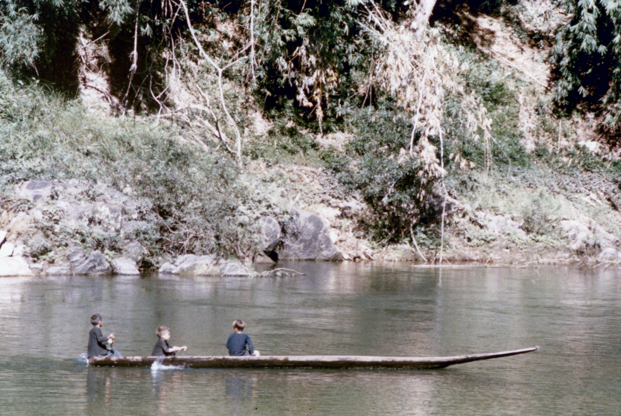 Hmong boys paddling a canoe on a river in Houa Khong Province