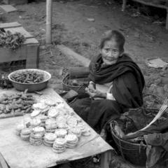 Older Lao woman offering rice cakes, fried bananas for sale