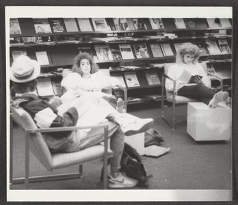 Students reading and sitting near the periodicals section in the library