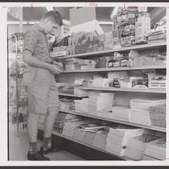 A boy examines school supplies in a drugstore display
