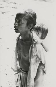A White Lahu (Lahu Hpu) father carries his child on his back in Houa Khong Province