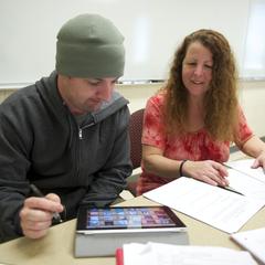 English professors help student on an iPad