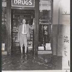 Man stands in floodwaters in the door of a drugstore
