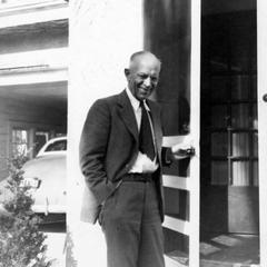 On the stoop of the family home in Madison, Wisconsin, door open and car visible in garage at left, ca. 1944