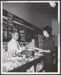 A pharmacist assists a customer at a drugstore counter