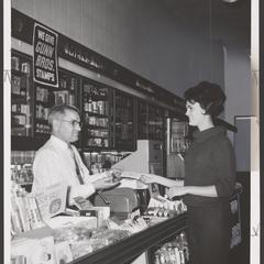 A pharmacist assists a customer at a drugstore counter