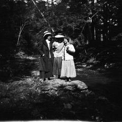 Three women standing on rock near river