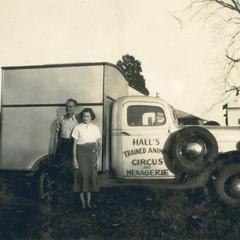 A man and woman standing beside Hall's Trained Animal Circus and Menagerie truck