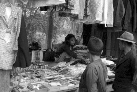 Woman merchant displaying notions and clothing at morning market