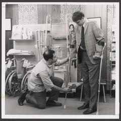 A pharmacist helps a customer select a pair of crutches