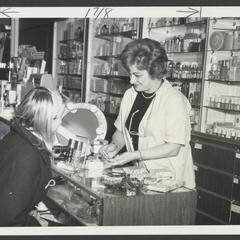 A saleswoman assists a young shopper at the cosmetics counter