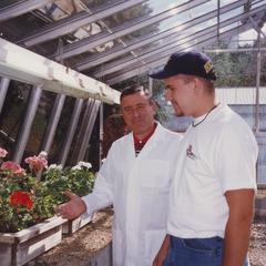 Biology professor Sami Saad with student in greenhouse