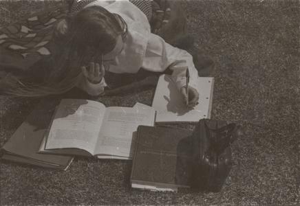 Student studying in grass on campus