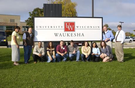 Staff and students pose in front of UW-Waukesha sign