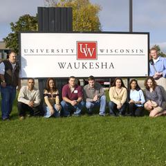 Staff and students pose in front of UW-Waukesha sign