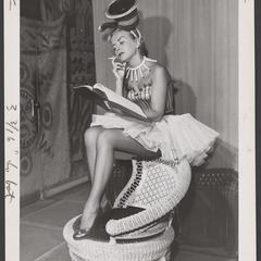 Woman dressed in a tobacco inspired costume smokes a cigarette as she reads