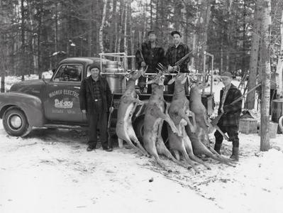 Hunters with deer hanging from truck