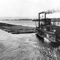 Sternwheel side view of the Kit Carson pushing a raft of logs