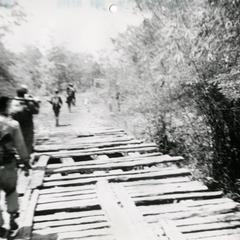 Soldiers on patrol cross primitive bridge on Route 11 between Attapu and Saravan
