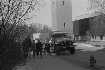 Students walk past army truck