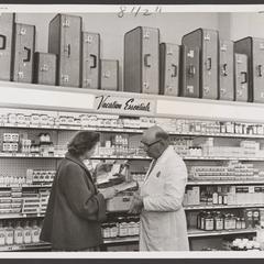 A woman inspects a suitcase from a drugstore vacation display
