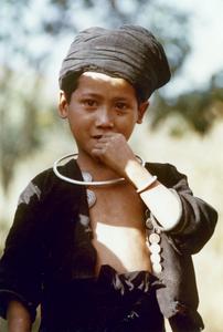 An Akha Burmese refugee boy stands in traditional clothing in Houa Khong Province