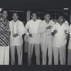 Seven men with drinks at a reunion of former cadets