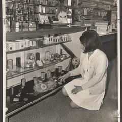 A saleswoman views items in a drugstore display